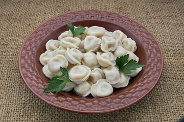 Dumplings in a brown plate on burlap