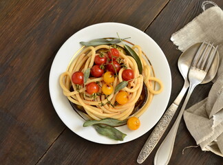 Pasta with baked eggplant, cherry tomato and sage, top view, copy space