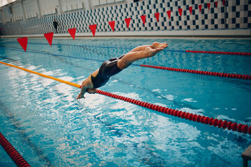 Young woman swimmer jump swims in swimming pool