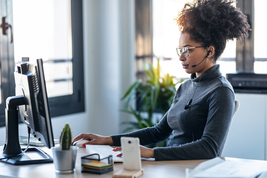 Beautiful Young Afro Business Woman Working While Making Video Call With Computer Sitting In The Office.