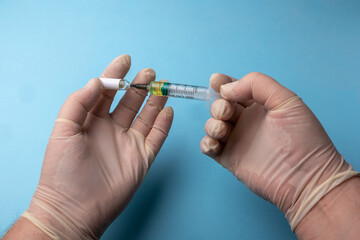 hands in medical gloves with a syringe and a vial of medicine on a blue background