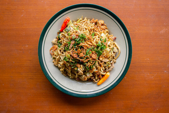 Mie Goreng Jawa or bakmi jawa or java noodle with
spoon and fork. Indonesian traditional street food noodles from central java or Yogyakarta, indonesia on wood background.