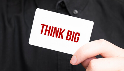 Businessman holding a card with text Think BIG,business concept