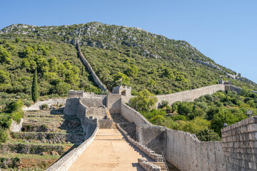 Narrow stone passage stairs on Wall of Ston aong hills in Croatia summer sunny morning