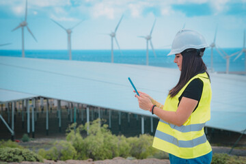 adult female engineer supervises solar panels and windmills in a renewable energy complex