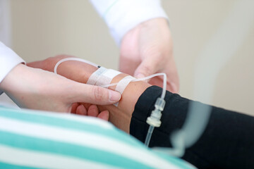 A female nurse is fixing the needle of the infusion set in the ward