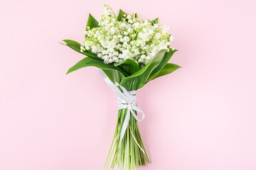 Spring lily of the valley flowers bouquet on pastel pink background. Flat lay. Top view. Wedding concept