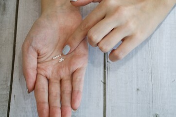 geöffnete Frauenhand auf der homöopathische Kügelchen liegen und mit dem Finger aufgezeigt...