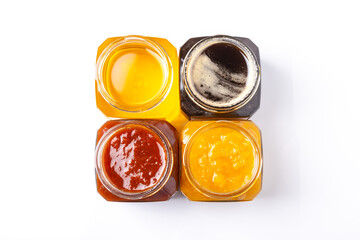 jars of peach and apricot jam and light and dark honey on a white background top view	
