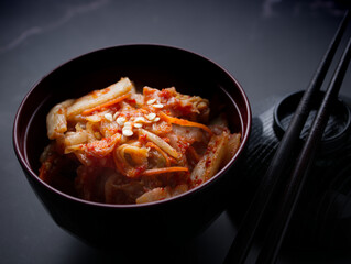 Korean food, Cabbage kimchi in black dish set on dark background.