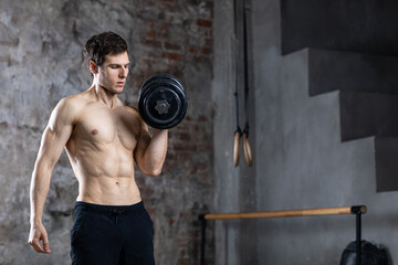 Strong athletic man with dumbbells  on dark grunge background.