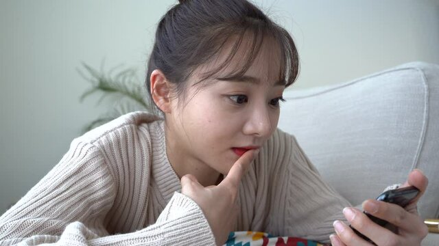 スマートフォンを見て驚く女性の表情