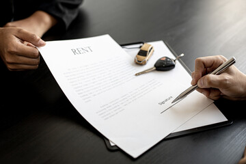An employee of the rental car company submits a car rental agreement for the renter to sign the rental agreement after discussing the rental details with the renter. Concept of car rental.