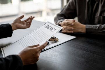 An employee of the rental car company is explaining the details and conditions of the car rental of the company and preparing the rental contract documents for the renter. Concept of car rental.