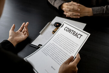 An employee of the rental car company is explaining the details and conditions of the car rental of the company and preparing the rental contract documents for the renter. Concept of car rental.