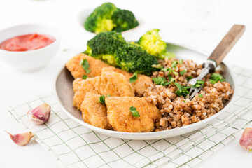 Homemade chicken nuggets with buckwheat and vegetables in a plate