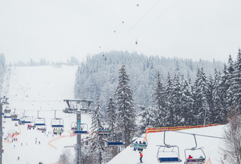 Ukraine. Bukovel - 02 FEBRUARY 2021. Ski lift with skiers and christmas trees. Part of the lift up...