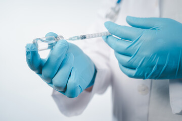 Doctor wear hand in blue gloves holding a syringe with liquid vaccines for children or older adults,Concept fight against virus covid-19 corona virus