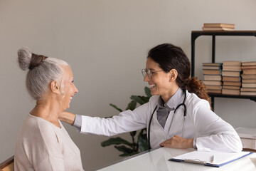 Side view smiling female doctor wearing uniform with glasses touching mature woman patient...