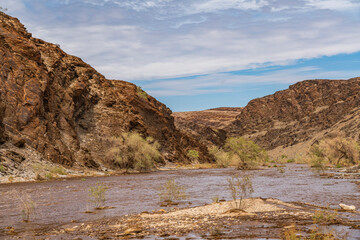 Gaub river in Namibia with much water after heavy rainfalls, Namib Naukluft Park, background cloudy...