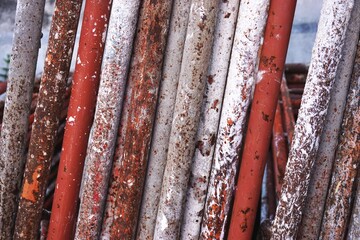 Metal scaffold pipes with rust and multicolor paint spatters