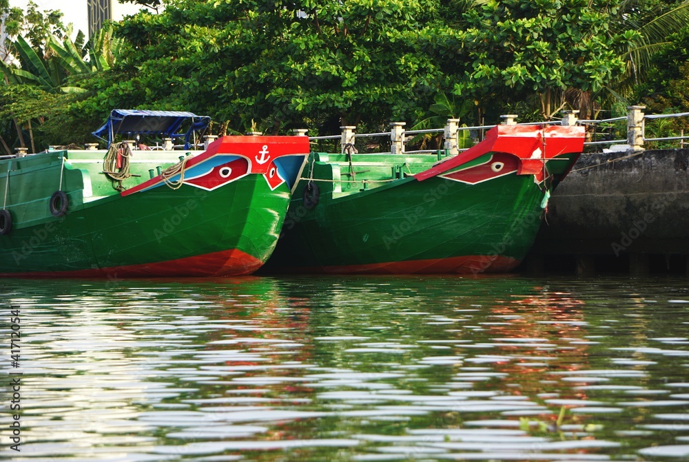 Wall mural Vintage green and red boats with painted eyes on the prow on a river in Southeast Asia