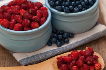 Red strawberry and blue bilberry on wooden background, organic food concept
