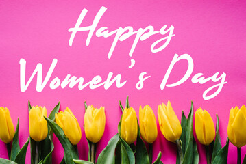 Row of yellow tulips on pink background with message. Holiday greeting card with text happy Women's Day. Top view, flat lay.