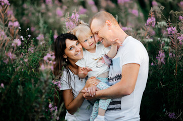 Fototapeta premium Image of young cute parents having fun together outdoors in the park with their daughter. Close-up.