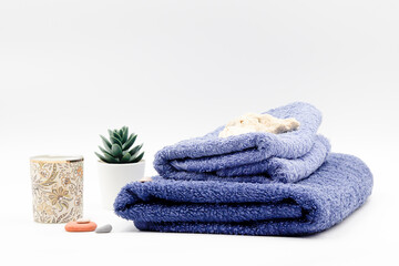 set consisting of blue towel with candle plant and stones.