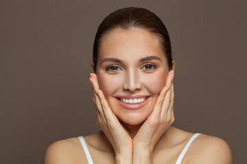 Healthy young woman smiling on brown background. Skincare and facial treatment concept