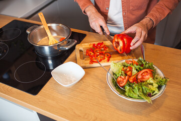 Cropped view of male cutting vegetables on chopping
