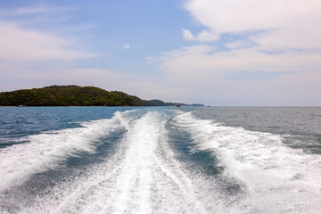 Water surface behind of fast moving motor boat. Trace tail of speed boat on water surface in the blue sea. 