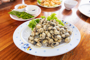 Fresh oyster on ice serve with garlic, spicy sauce and vegetables acacis on table seafood meals.