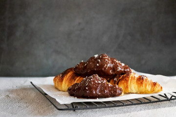 Dark chocolate croissants with nut and flower of salt on top in vintage dark stone background. Tasty and freshly croissants. 