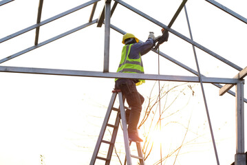 Roofing workers working on roof trusses on a construction site are searching for and analyzing unfinished construction projects.