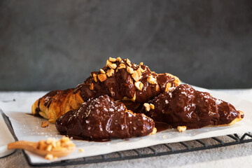 Dark chocolate croissants with nut and flower of salt on top in vintage dark stone background. Tasty and freshly croissants. 
