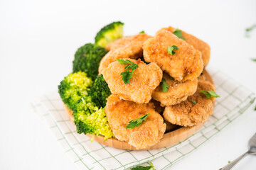 Homemade chicken nuggets with vegetables (broccoli) in a plate on a white background, selective focus