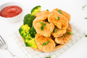 Homemade chicken nuggets with vegetables (broccoli) in a plate on a white background, selective focus