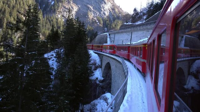 Europe, Switzerland Alps , Poschiavo February 2021 - Live shot from the window  of the  Bernina Express, red train  pass in Ospizio Bernina station -  White lake ( lago bianco ) frozen 