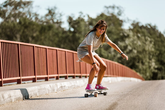 Young sporty woman riding on the skateboard on the road.