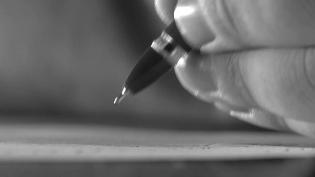 writes with an old pen on paper. close-up. black and white. Senior man writing down letters on a piece of paper. Close up of Old male hands writing