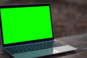 A laptop with a green screen on the table