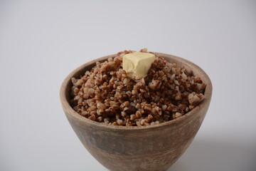 Bowl of tasty buckwheat porridge with piece of butter on the top