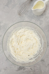 Ready cream of cream cheese in a bowl to make the cake on a gray concrete background. Top view.