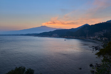 sunset on the bay of Taormina With the smoking Etna Volcano, which dominates the scene, and the sky is colored