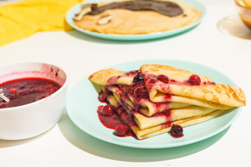 blini pancakes with red berry jam close-up on a blue plate on a light background . traditional Russian holiday is a symbol of spring and sweet dessert