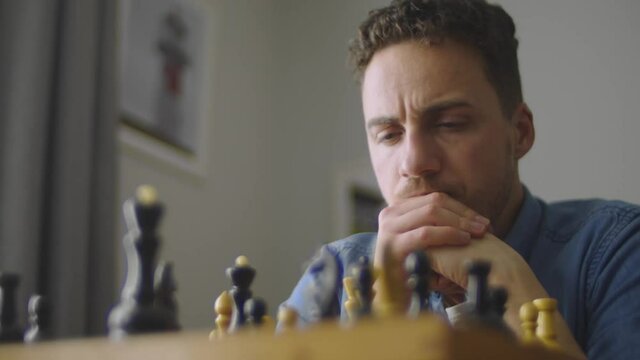 A young handsome guy is thinking about the next move in a difficult game