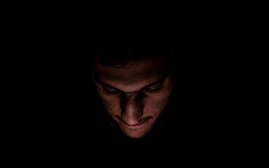 Portrait of middle eastern guy checking his phone in a dark room