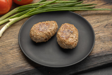Fried cutlet in a black plate on a wooden table